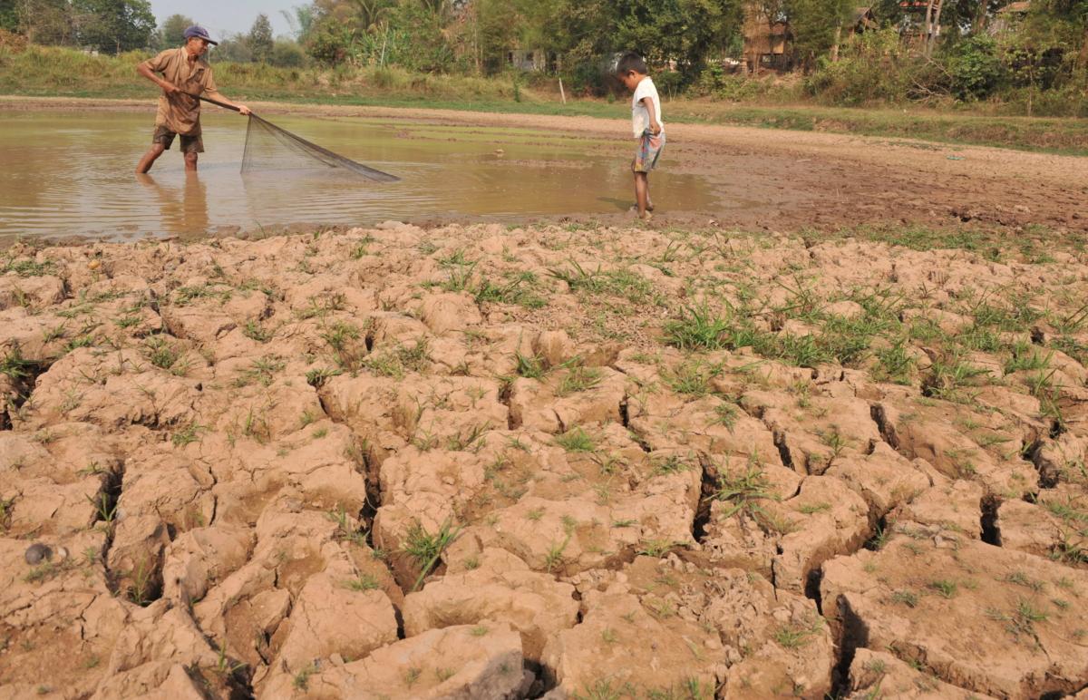 Farmer Phia Paokhammacham (L) and his son fish on the family drought-hit rice field near to Mekong River at Mai village near Vientiane, Laos, on March 27, 2010. (Hong Dinh Nam/AFP via Getty Images)
