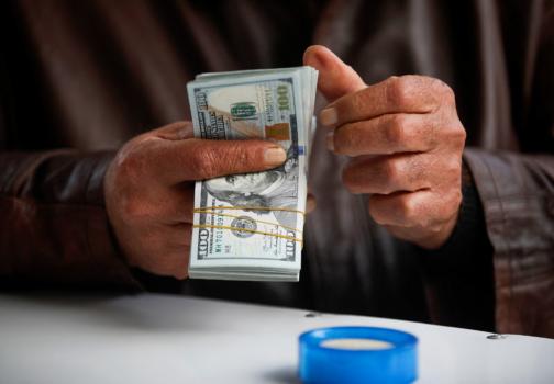 A man counts US dollar banknotes at al-Kifah stock market in Baghdad on Dec. 27, 2022. (AHMAD AL-RUBAYE/AFP via Getty Images)