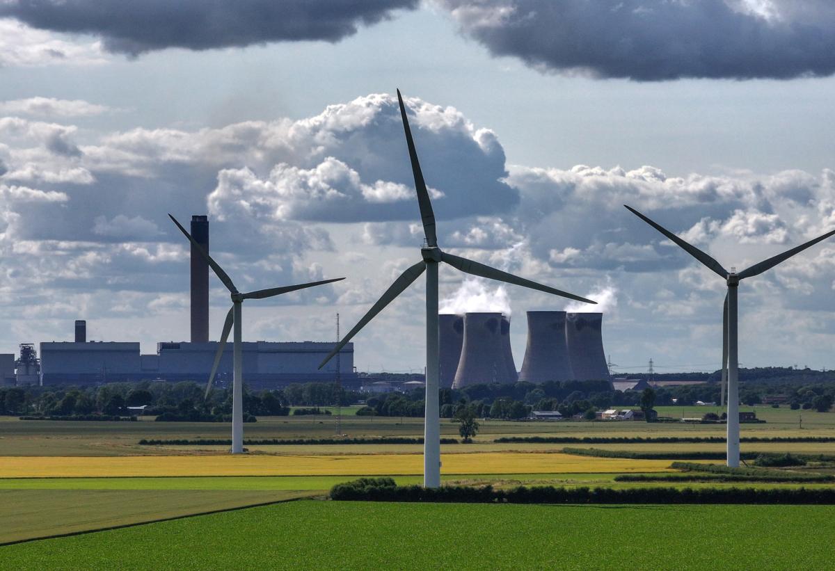 Wind turbines generate electricity as the Drax Power Station in the background also generates electricity in Selby, England, on June 29, 2023. (Christopher Furlong/Getty Images)