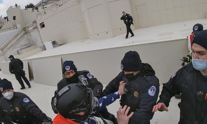 Protester Christopher Quaglin grabs the jacket of a Capitol Police officer on the west plaza of the U.S. Capitol in Washington on Jan. 6, 2021. (Special to The Epoch Times)