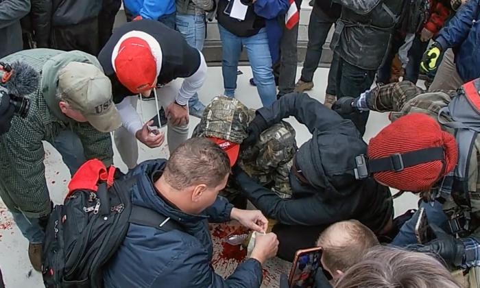 Bystanders try to stop the profuse bleeding from the wounded Joshua Black, who was shot in the face at the U.S. Capitol in Washington on Jan. 6, 2021. (Special to The Epoch Times)