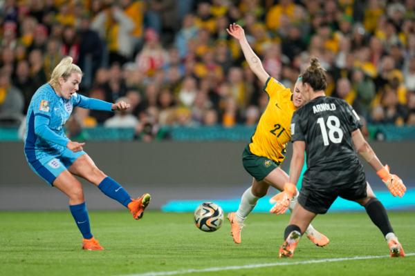 England's Lauren Hemp, left, scores her side's second goal past Australia's goalkeeper Mackenzie Arnold, as Australia's Ellie Carpenter, centre, tries to block during the Women's World Cup semifinal soccer match between Australia and England at Stadium Australia in Sydney, Australia on Aug. 16, 2023. (Abbie Parr/AP Photo)