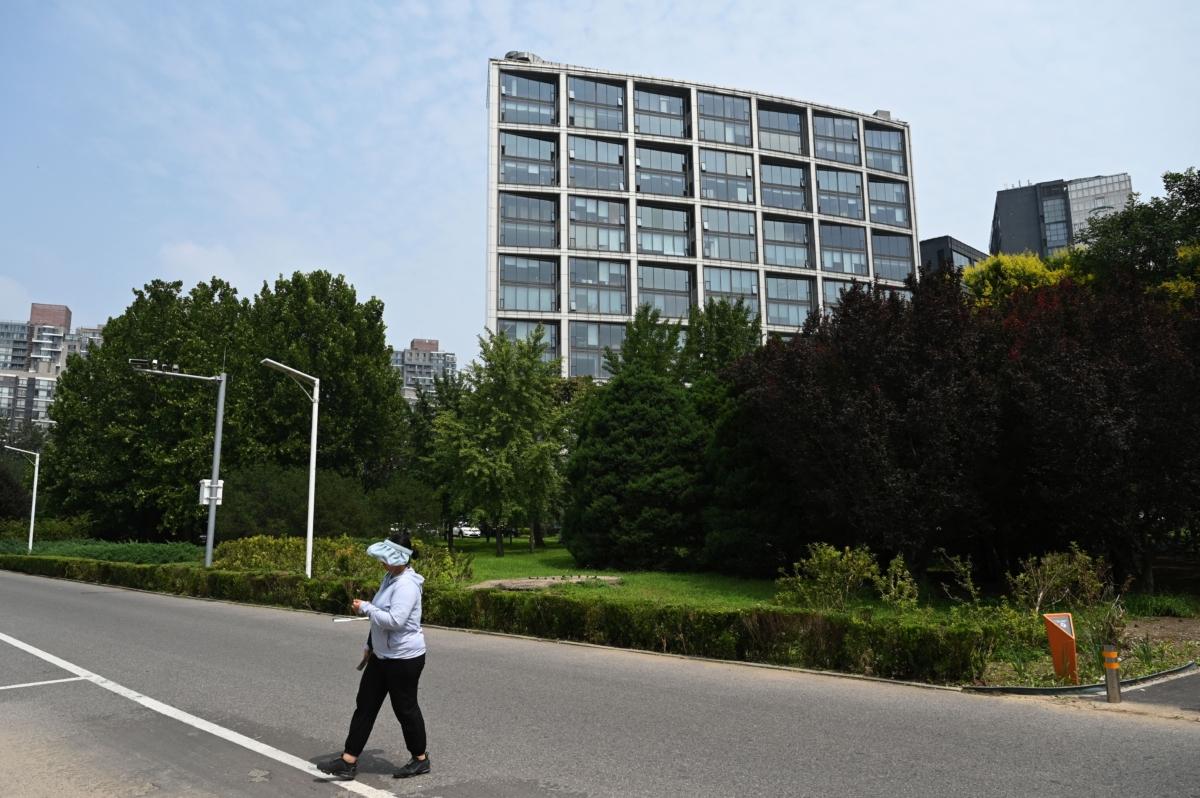 A woman walks by the Beijing office of Zhongrong International Trust Co., partly owned by the Zhongzhi Enterprise Group, in Beijing on Aug. 17, 2023. (Greg Baker/AFP via Getty Images)