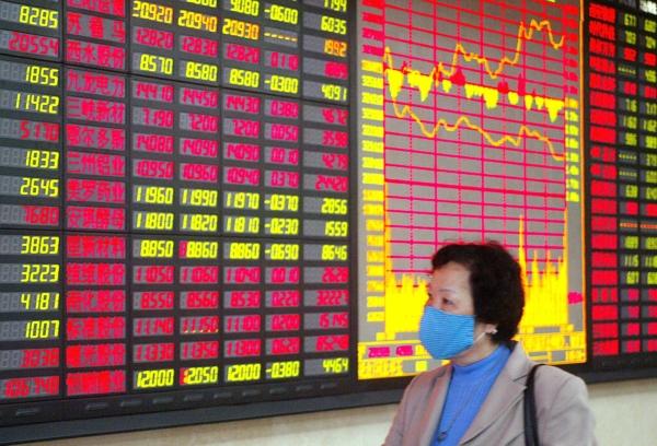 An investor walks in front of the share-prices index display at a stocks bourse in Shanghai on May 12, 2003. (Liu Jin/AFP via Getty Images)