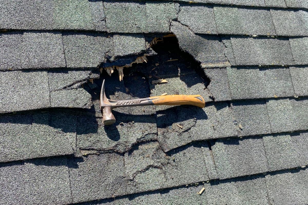 A hammer near damage to a home in Shirley, Mass., on Aug. 14, 2023, where a chunk of ice landed on the roof on the previous day. (Jeff Ilg via AP)