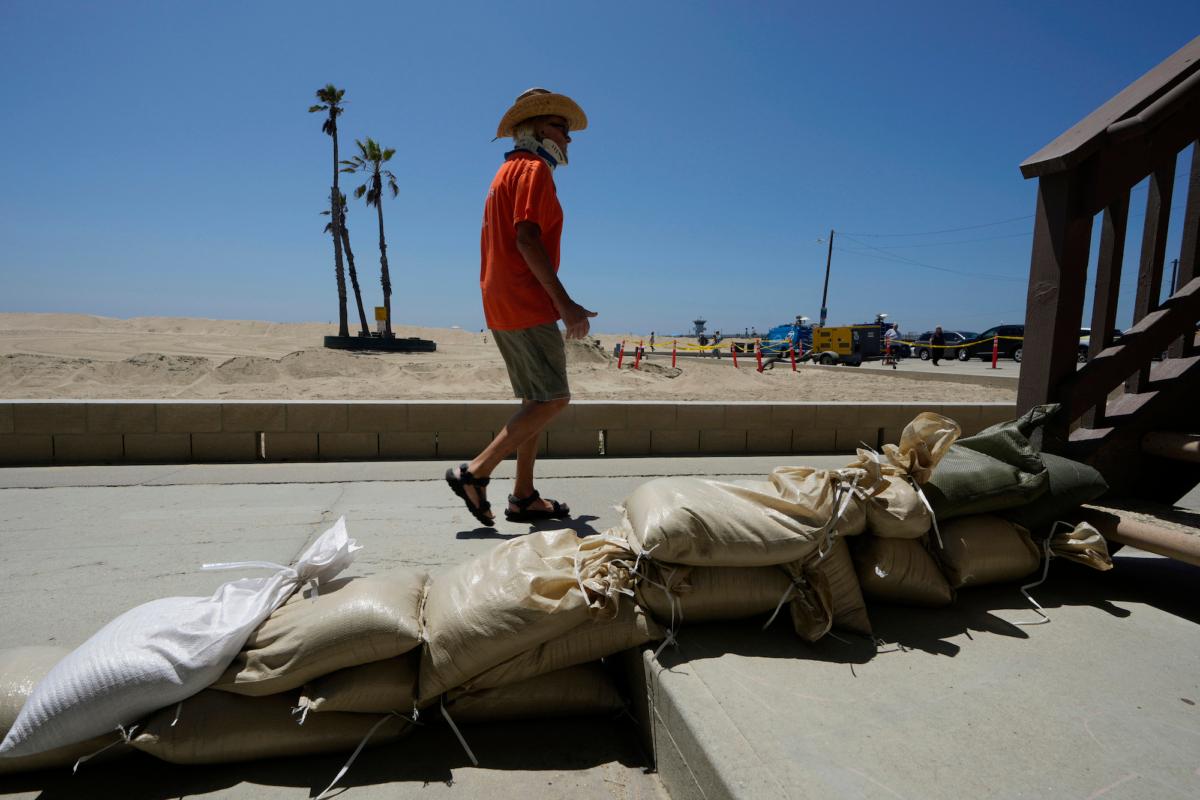 A Seal Beach resident walks past a home protected with sandbags in Seal Beach, Calif., on Aug. 18, 2023. (Damian Dovarganes/AP Photo)