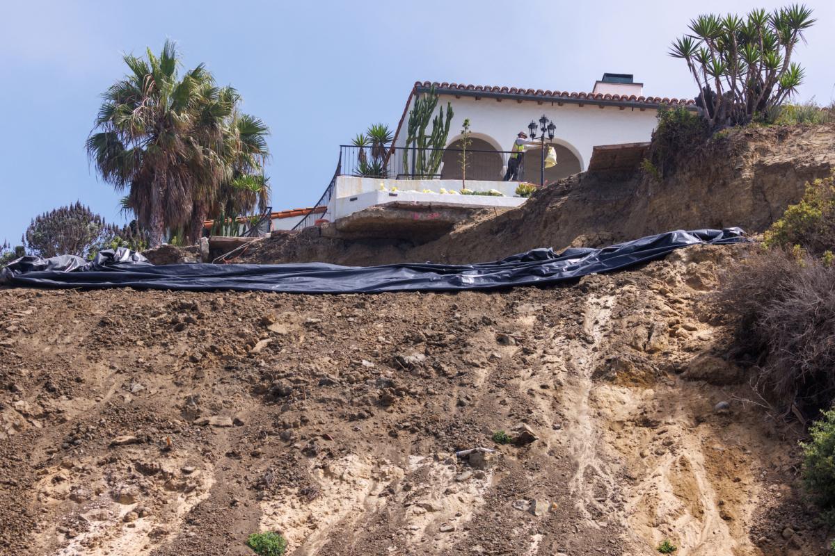 Workers prepare to cover a slide-ridden hillside with plastic tarp in the hopes to protect it from the rain expected with upcoming storm Hilary in San Clemente, California, on Aug. 18, 2023. (Mike Blake/Reuters)