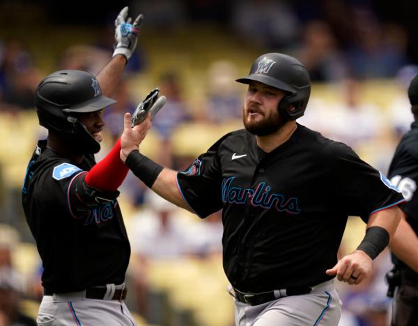 Miami Marlins' Jake Burger, right, is congratulated by Jesus Sanchez, left, after scoring off a double by Bryan De La Cruz during the fourth inning of the first baseball game of a doubleheader against the Los Angeles Dodgers in Los Angeles on Aug. 19, 2023. (Ryan Sun/AP Photo)