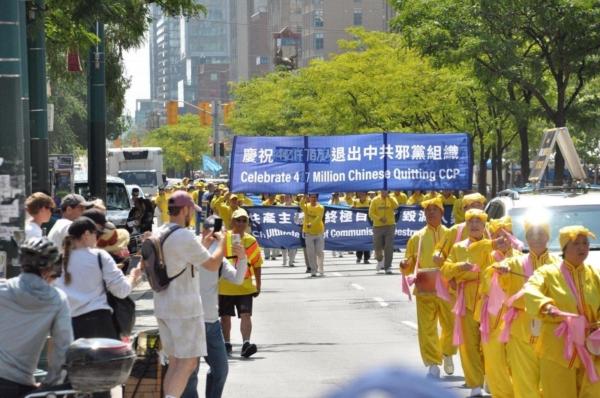 People watch as Falun Gong adherents march in a parade in downtown Toronto on Aug. 19, 2023, to celebrate 417 million Chinese people quitting the Chinese Communist Party and its affiliated organizations. (Evan Ning/The Epoch Times)