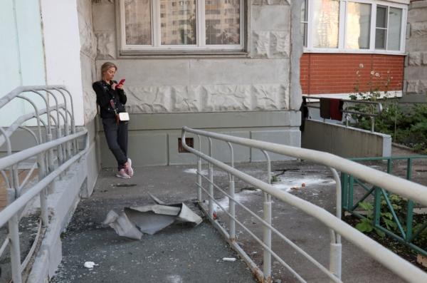 A woman checks her phone next to debris, following a reported drone attack in Krasnogorsk, Russia, on Aug. 22, 2023. (Stringer/Reuters)