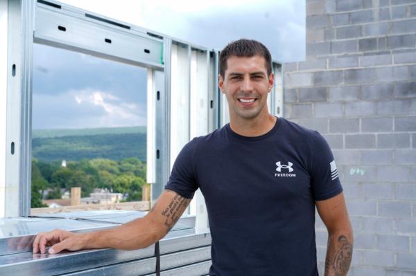 Cory Puopolo stands on the unfinished rooftop of the future Front Hotel in downtown Port Jervis, N.Y., on Aug. 17, 2023. (Cara Ding/The Epoch Times)