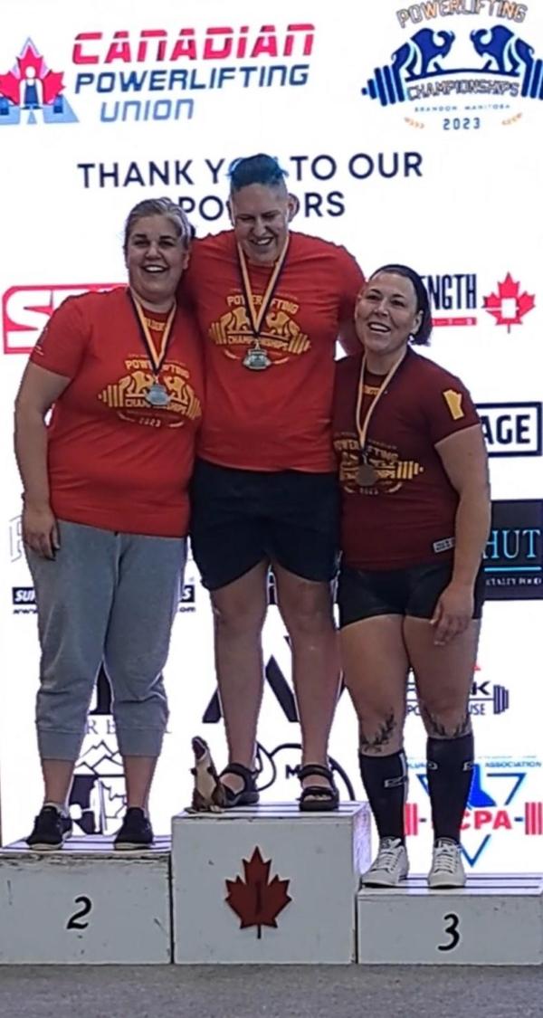 Anne Andres (middle), on the podium at the Canadian Powerlifting Union Western Championship on Aug. 13 in Brandon, Manitoba, with second place winner SuJan Gill (L), and third place winner Michelle Kymanick (R), in women's powerlifting. (Photo Courtesy of Anne Andres)