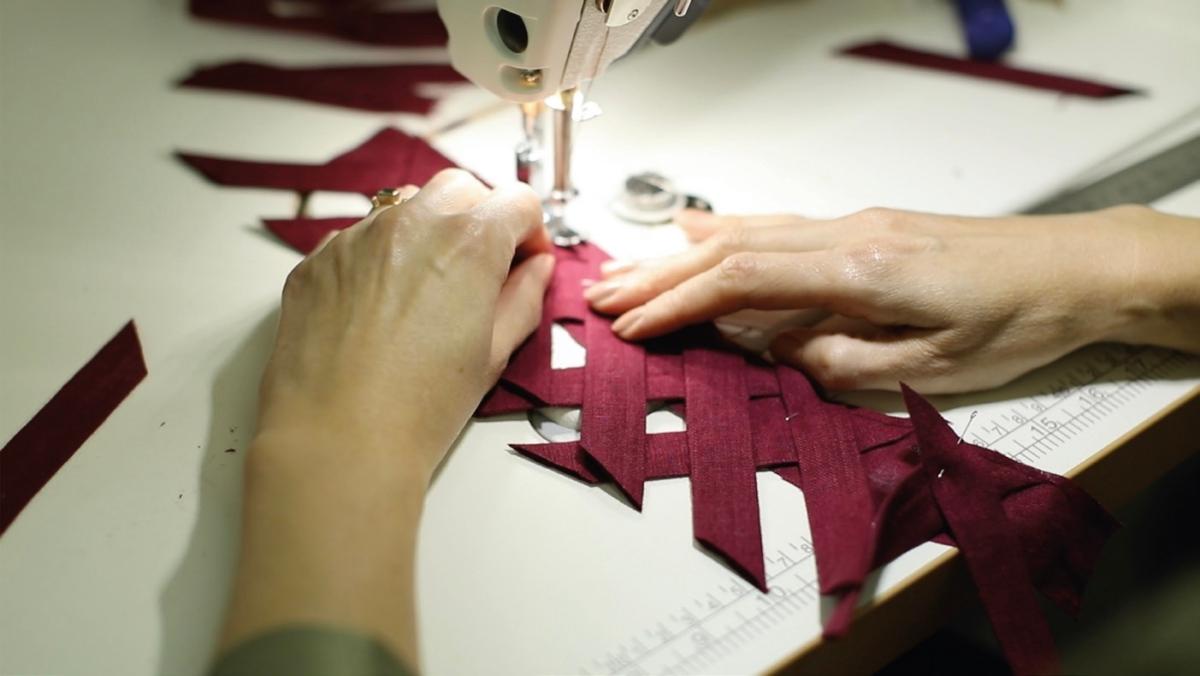 A seamstress sews the lattice-work sleeve detail for a Meg Dress. (Courtesy of Little Women Atelier)
