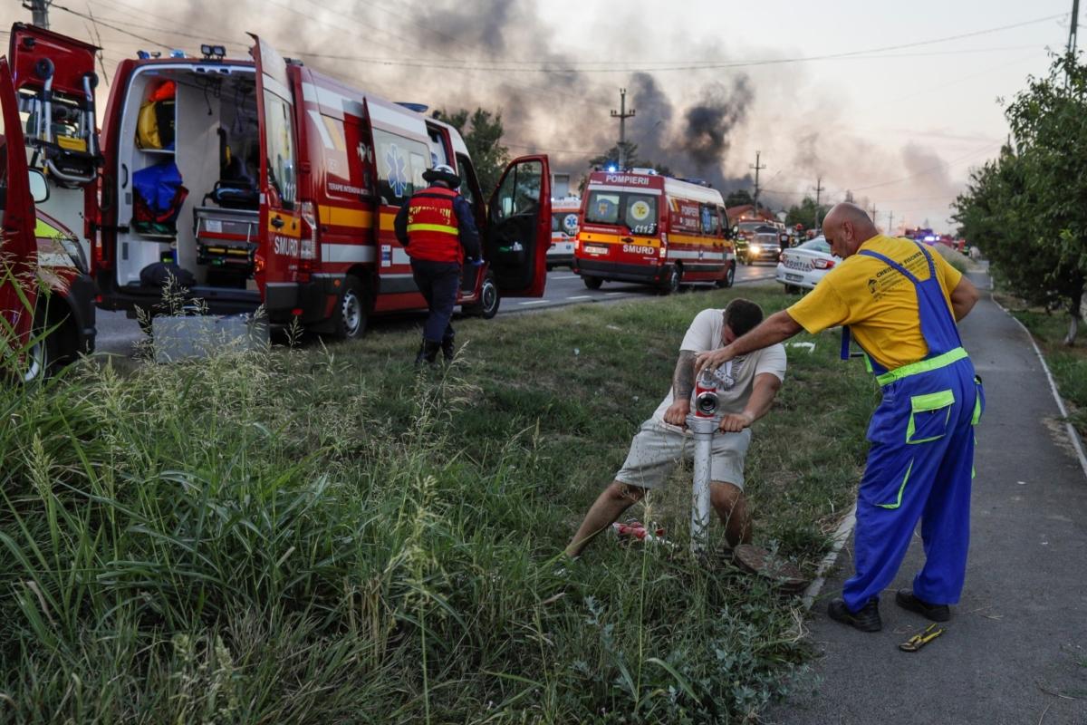 People use a fire hydrant as flames rise after an explosion at a LPG station in Crevedia, near Bucharest, Romania, on Aug. 26, 2023. (Inquam Photos/Octav Ganea via Reuters)