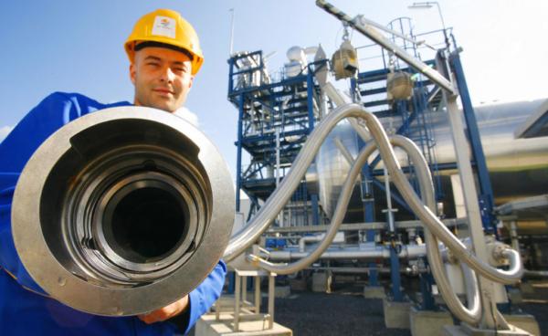 An employee poses with a pipe used to carry liquid CO2 at the "Schwarze Pumpe" ("Black Pump") power station in Werder near Berlin, on Sept. 8, 2008. (Michael Urban/DDP/AFP via Getty Images)