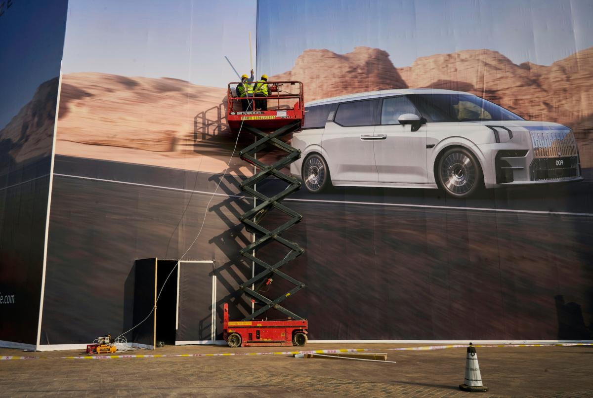 Workers install a large billboard for the Chinese electric car maker Zeekr in Beijing, China, on March 31, 2023. (Kevin Frayer/Getty Images)