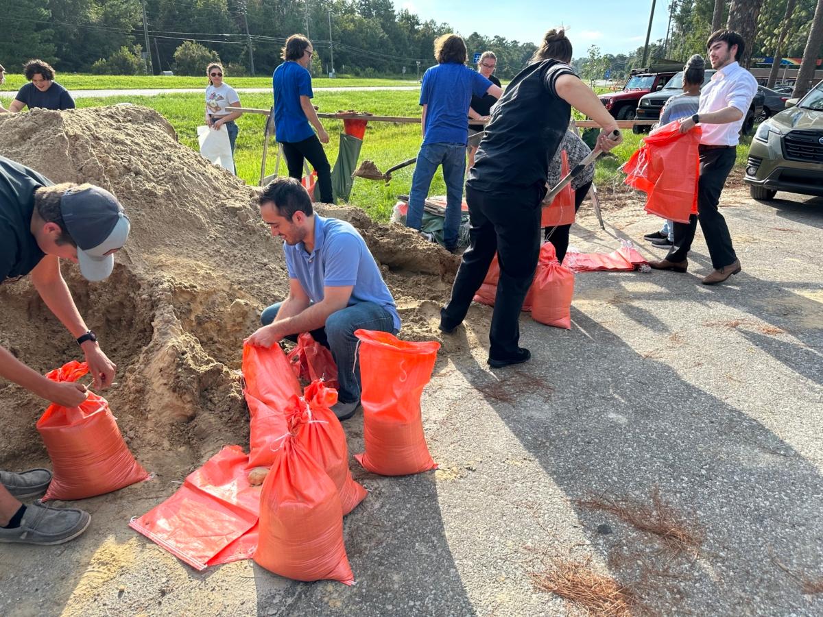 Strangers help each other fill sandbags—about 36 hours ahead of Tropical Storm Idalia's projected landfall on Florida's Gulf Coast—at a makeshift Alachua County Public Works facility in Alachua, Fla., on Aug. 28, 2023. (Nanette Holt/The Epoch Times)