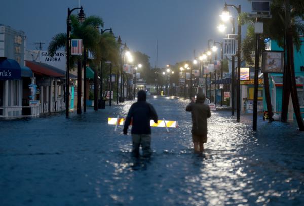 Reporters wade through flood waters inundating Dodecanese Boulevard in Tarpon Springs, Fla., early on August 30, 2023 as Hurricane Idalia passes offshore. (Photo by Joe Raedle/Getty Images)