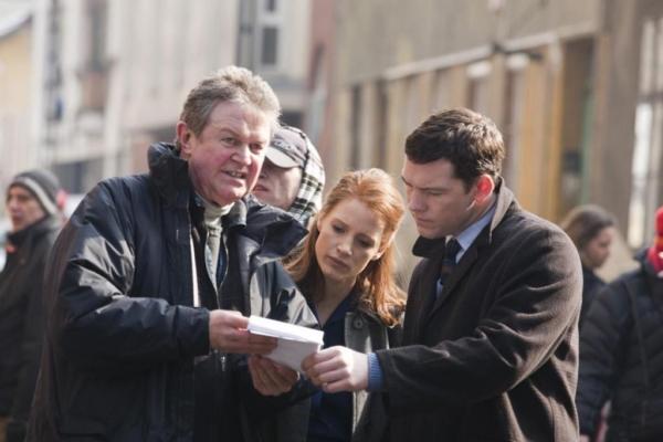 (L–R) Director John Madden with Jessica Chastain and Sam Worthington on the set of "The Debt." (Focus Features)