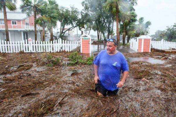 Daniel Dickert wades through water in front of his home where the Steinhatchee River overflowed in Steinhatchee, Fla., on Aug. 30, 2023, after the arrival of Hurricane Idalia. (Douglas R. Clifford/Tampa Bay Times via AP)