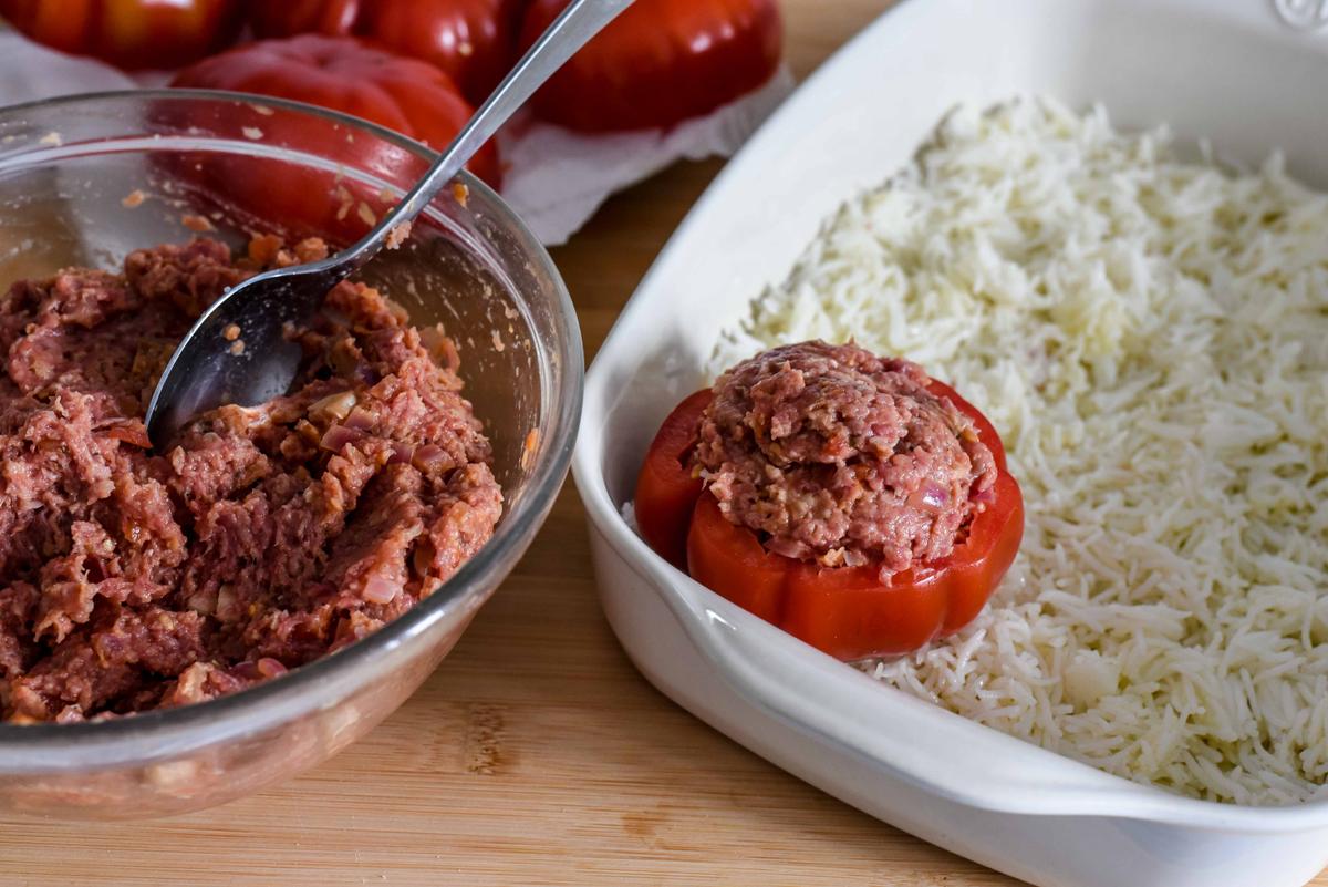 Pack the stuffing into the hollowed tomatoes and stand upright on top of the rice. (Audrey Le Goff)