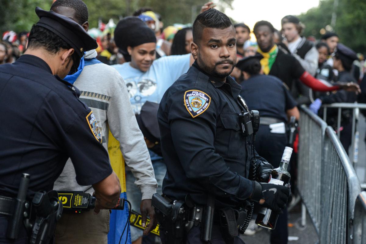 A police officer confiscates a bottle of alcohol during a Caribbean street carnival called J'Ouvert in the Brooklyn borough of New York City on Sept. 4, 2017. J'Ouvert, which draws tens of thousands of costumed celebrants, has been plagued by violence in recent years, resulting in new intensive security measures. (Stephanie Keith/Getty Images)