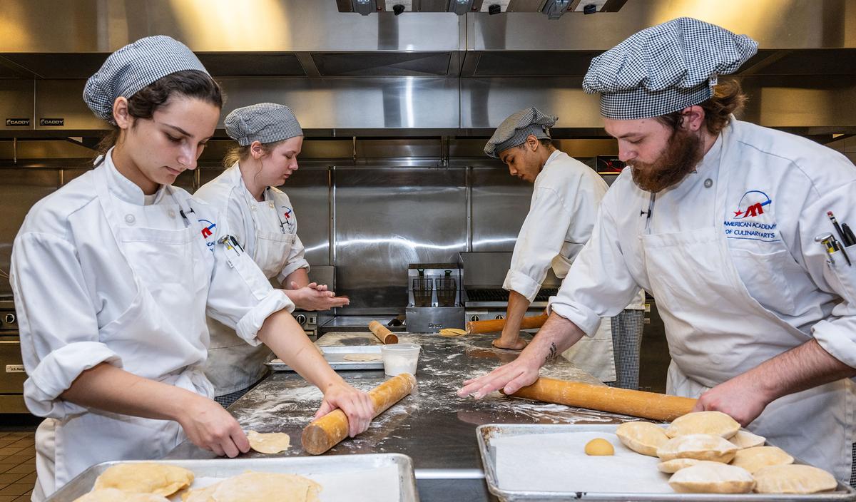 From left, Savannah Kopyar, Cassandra Kagle, Josiah Idley and Hunter Bierly, all culinary students from Pittsburgh Technical College, roll dough to make chapati bread on Monday, July 24, 2023. (Lucy Schaly/Pittsburgh Post-Gazette/TNS)