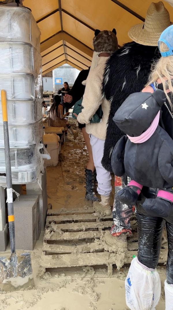 People use plastic bags to cover their shoes as others are seen with their boots covered in mud at the site of the Burning Man festival in Black Rock, Nevada, on Sept. 2, 2023. (Paul Reder/via Reuters)