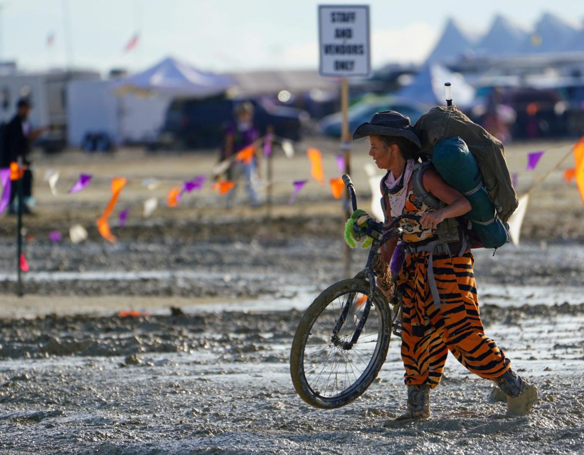 A Burning Man participant walks through the mud after a severe rainstorm left tens of thousands of revelers attending the annual festival stranded in mud in Black Rock City, in the Nevada desert, on Sept. 3, 2023. (Trevor Hughes/USA Today Network via Reuters)