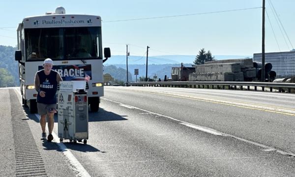 Retired United Airlines flight attendant Paul Veneto pushes an airplane beverage cart along Route 30 between Everett and Bedford, Pa., on Sept. 3, 2023. (Courtesy Paulies Push)
