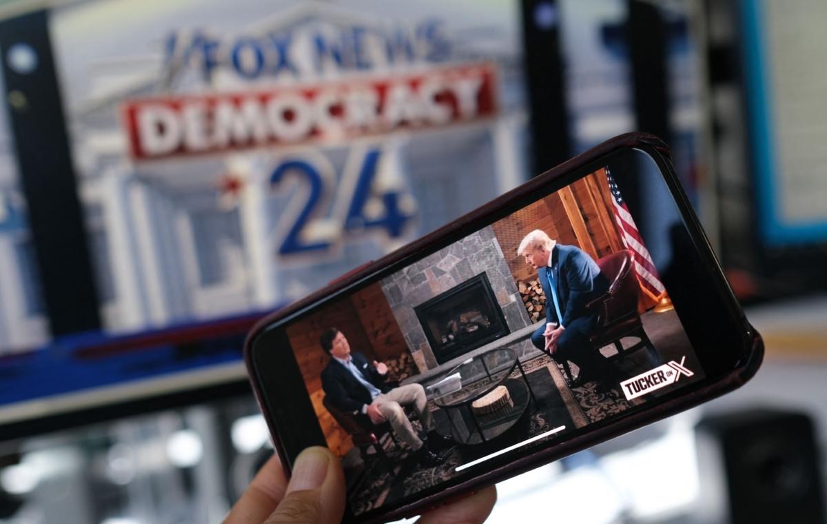 An illustration photo of Tucker Carlson's interview with former U.S. President Donald Trump that aired on X (formerly Twitter) on the same night of the first Republican Presidential primary debate in Milwaukee, as seen on a smartphone ahead of the debate on Aug. 23, 2023. (Chris Delmas/AFP via Getty Images)