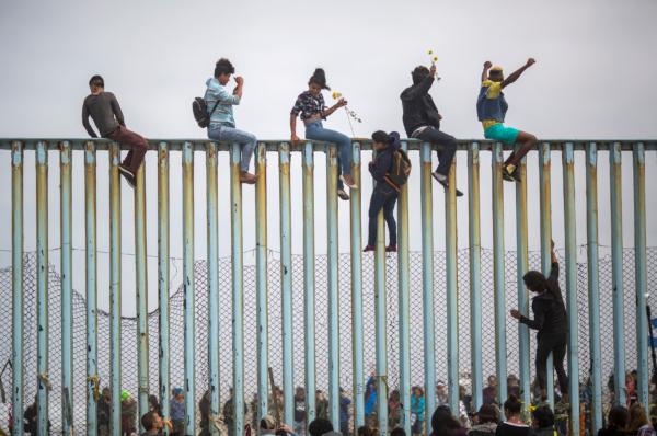  Illegal immigrants climb a section of the U.S.–Mexico border fence in Tijuana, Mexico, on April 29, 2018. (David McNew/Getty Images)