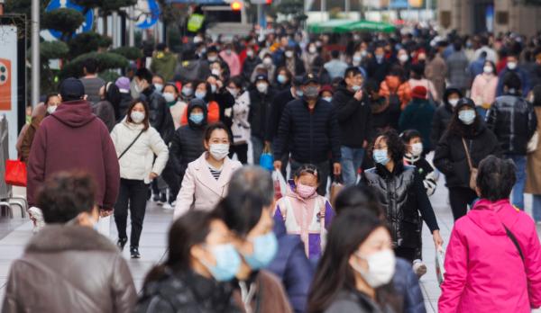 People with protective masks walk along Nanjing Road in Shanghai on Dec. 11, 2022. (Hu Chengwei/Getty Images)