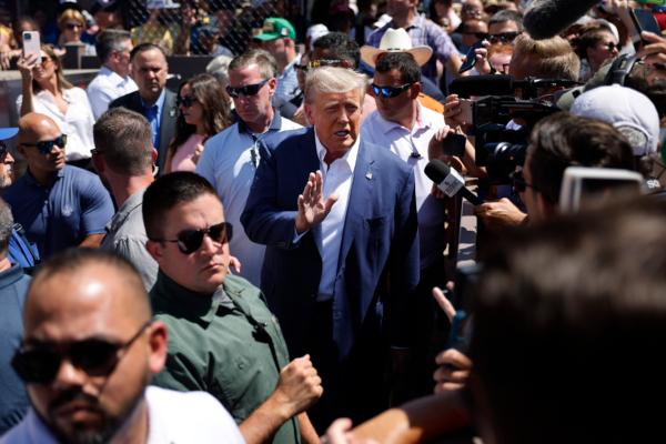 Surrounded by campaign staff and members of the U.S. Secret Service, Former U.S. President Donald Trump (center) waves to supporters as he visits the Iowa Pork Producers Tent at the Iowa State Fair in Des Moines, Iowa, on Aug. 12, 2023. (Chip Somodevilla/Getty Images)