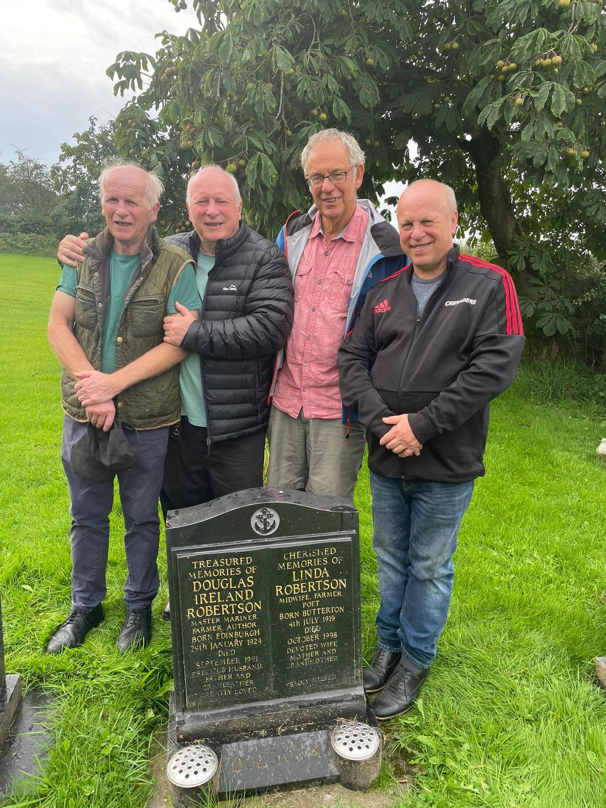 The four survivors at the gravestone of Dougal Robertson and Linda (Lyn) Robertson on Sept. 10, 2023. (Courtesy of The Robertson Family Archive)
