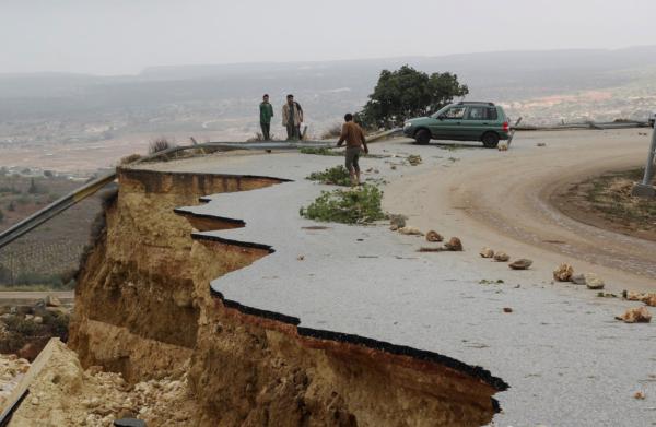 People stand in a damaged road as a powerful storm and heavy rainfall flooded hit Shahhat city, Libya, on Sept. 11, 2023. (Omar Jarhman/Reuters)