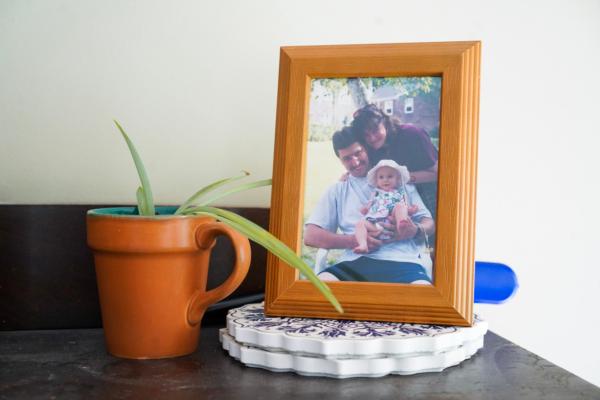Elizabeth Miller is held by her father, Douglas Miller, with her mother in the background in a framed picture at her house in Port Jervis, N.Y., on Sept. 7, 2023. (Cara Ding/The Epoch Times)