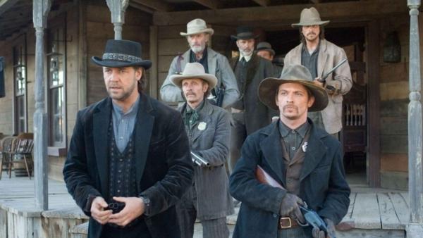 A posse (with Christian Bale, back R) leads Ben Wade (Russell Crowe, L) on the way to the train station, which will take Wade to Yuma. (Lionsgate)