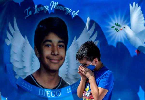 Eric Henry, 9, of Moreno Valley, prays during a 2020 memorial in the parking lot of Landmark Middle School to commemorate the death of Diego Stolz, who was fatally assaulted in September 2019 by two other students in Moreno Valley, Calif. (Terry Pierson/The Orange County Register via AP)