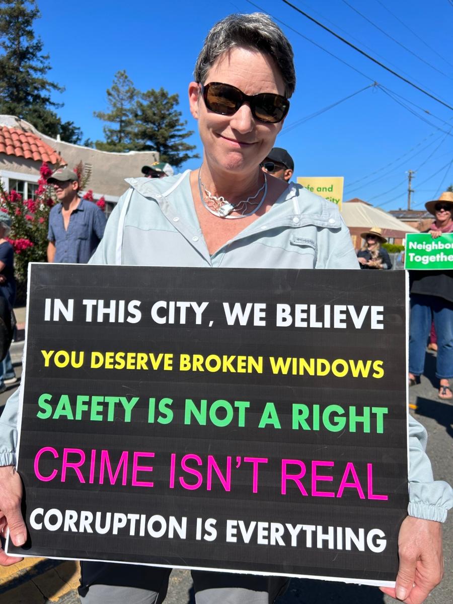 A woman holds a sarcastic sign as locals concerned about public safety issues gather outside of a "Community Safety" meeting attended by local government and law enforcement officials at the Genesis Worship Center in East Oakland, Calif., on Sept. 9, 2023. (Courtesy of Loretta Breuning)