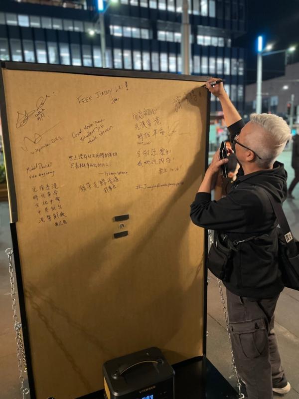 Hong Kongers in Sydney sign on the back of the neon light exhibit to show their support. (Tom Yu/The Epoch Times)