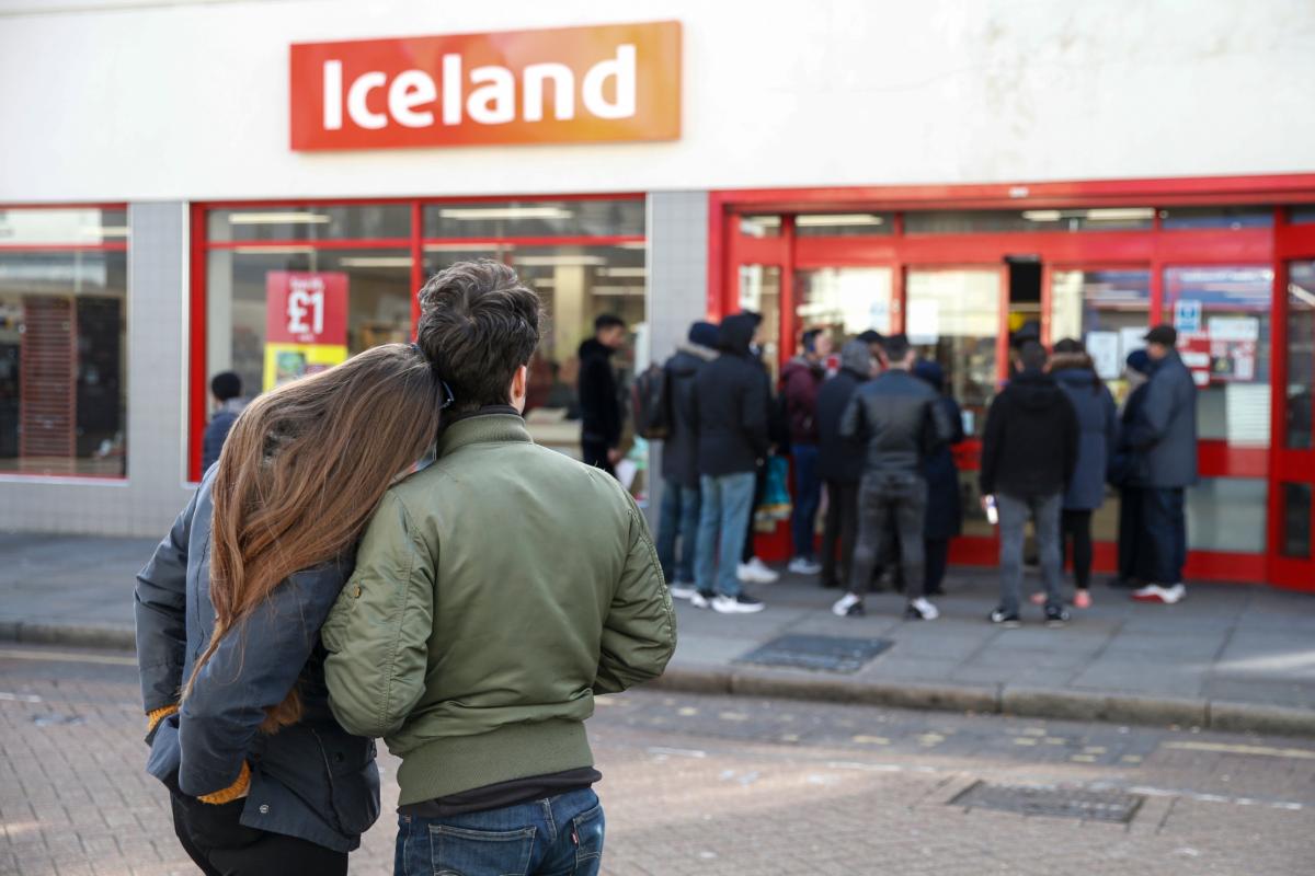 People line up outside an Iceland supermarket on Roman Road in Bow, London, on March 21, 2020. (Hollie Adams/Getty Images)