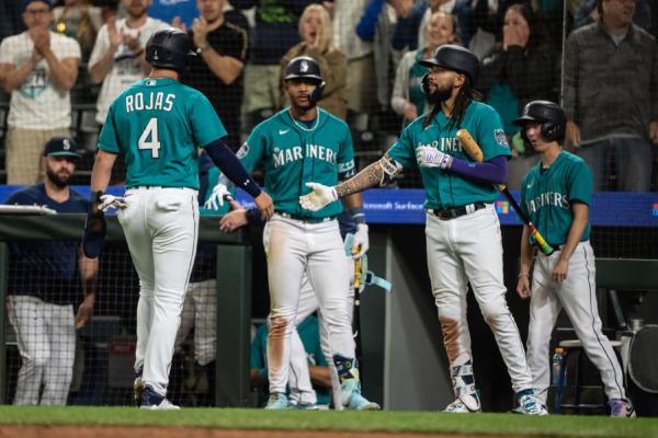 Josh Rojas (4) of the Seattle Mariners is congratulated by J.P. Crawford (3), (2R) and Julio Rodriguez (44) of the Seattle Mariners (C) after scoring a run on a hit by Mike Ford (20) during the tenth inning of a game against the Los Angeles Dodgers at T-Mobile Park in Seattle on Sept. 16, 2023. (Stephen Brashear/Getty Images)