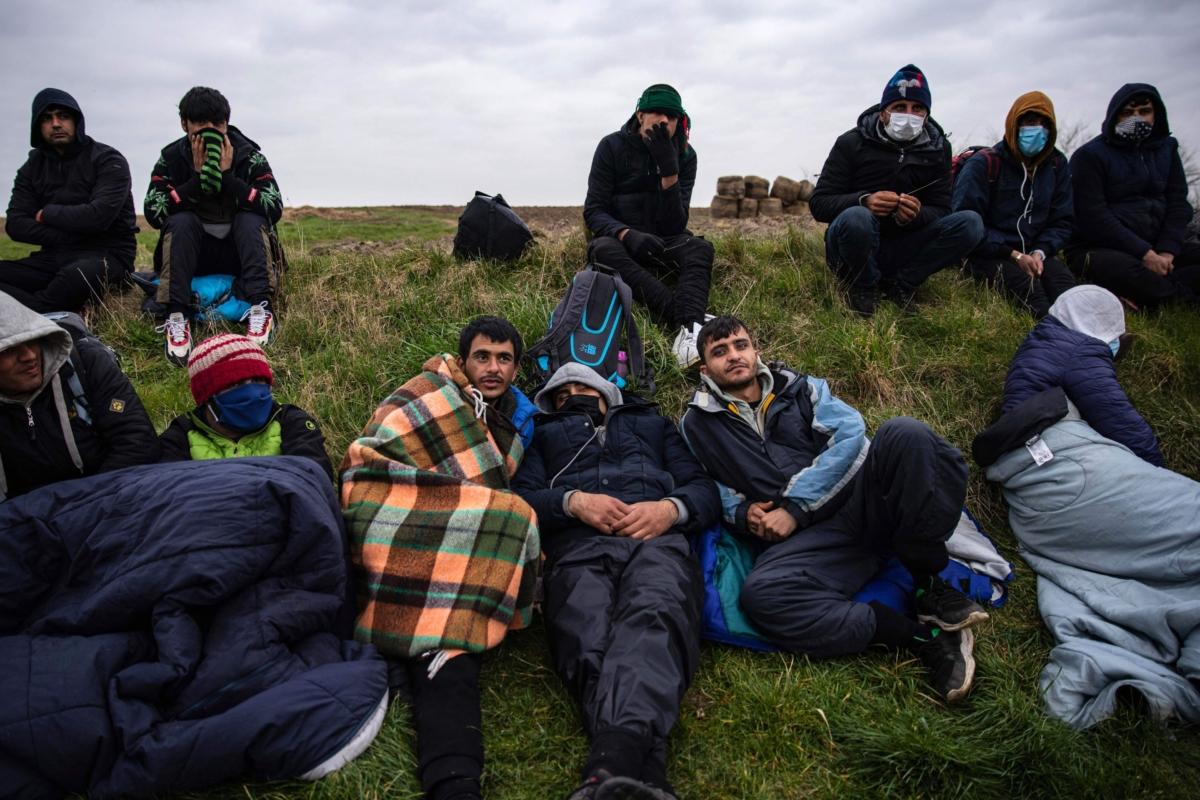 Migrants wait for a bus to go back to their makeshift camps after a failed crossing attempt in Calais, north of France, on March 16, 2022. (Sameer Al-doumy/AFP via Getty Images)