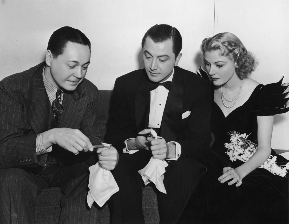 Magician Paul LePaul (L) shows actors Robert Young and Florence Rice a magic trick, which involves cutting a napkin with scissors, on the set of the film "Miracles for Sale" in 1939. (Hulton Archive/Getty Images)