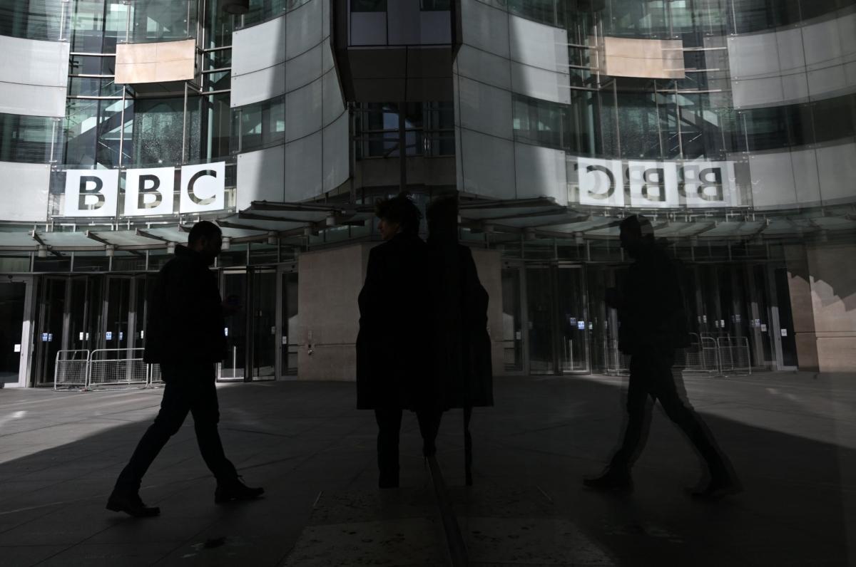 A pedestrian is reflected in the glass facade while walking past the BBC Headquarters at the Broadcasting House in central London on Oct. 6, 2022. (Justin Tallis/AFP via Getty Images)