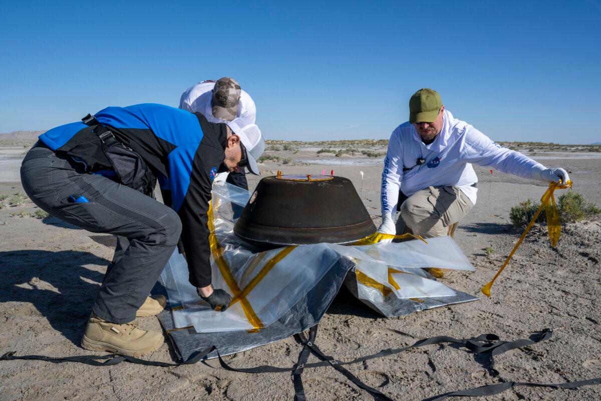 Lockheed Martin Mission Operations Assurance Lead Graham Miller (L), and recovery specialists Michael Kaye (2nd L), and Levi Hanish (R), prepare the sample return capsule from NASA's OSIRIS-REx mission for transport shortly after it landed in Utah on Sept. 24, 2023. (Keegan Barber/NASA via Getty Images)