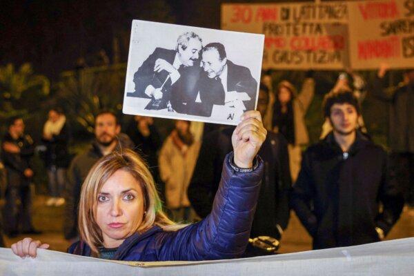 A woman displays a photograph that became iconic in Italy and shows top anti-mafia prosecutors Giovanni Falcone, (L), and Paolo Borsellino, during a demonstration in the streets of Palermo, Sicily, Italy, on Jan. 16, 2023. (Alberto Lo Bianco/LaPresse via AP)
