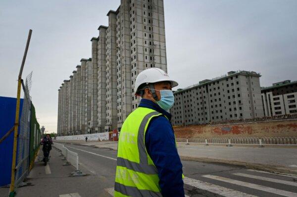 A worker watches as he prepares to cross a street outside a construction site in Beijing on April 26, 2022. (Wang Zhao/AFP via Getty Images)