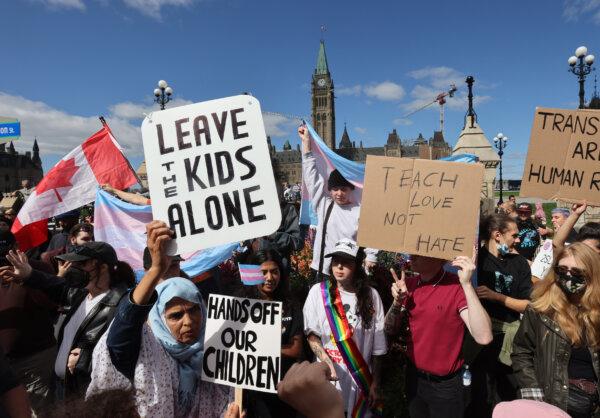 Protesters hold signs in front of counter-protestors at a demonstration against sexual orientation and gender identity programs in schools, in front of Parliament Hill in Ottawa, on Sept. 20, 2023.